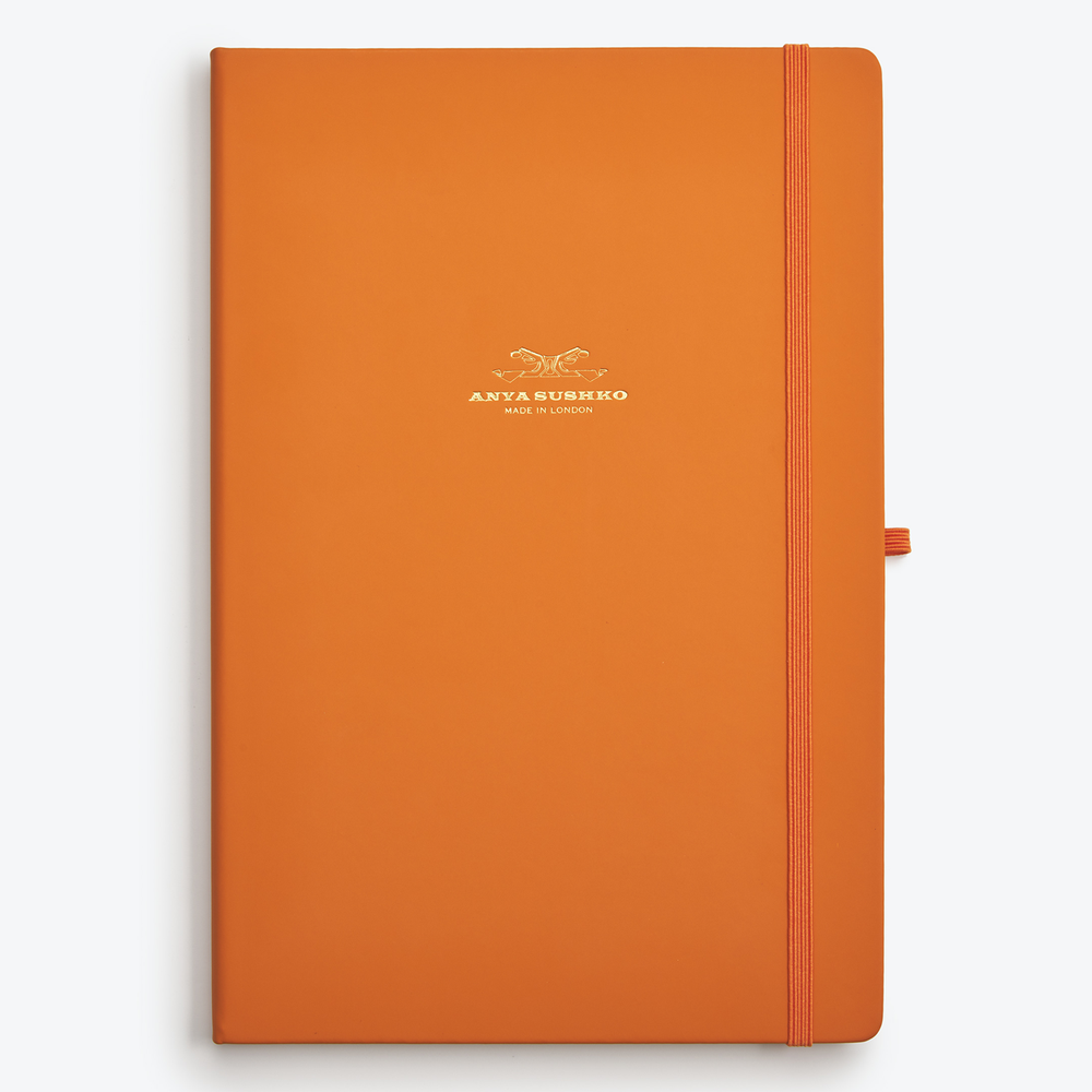 An orange A4 hardback refill notepad with the Anya Sushko brand logo embossed in gold foil on the cover.