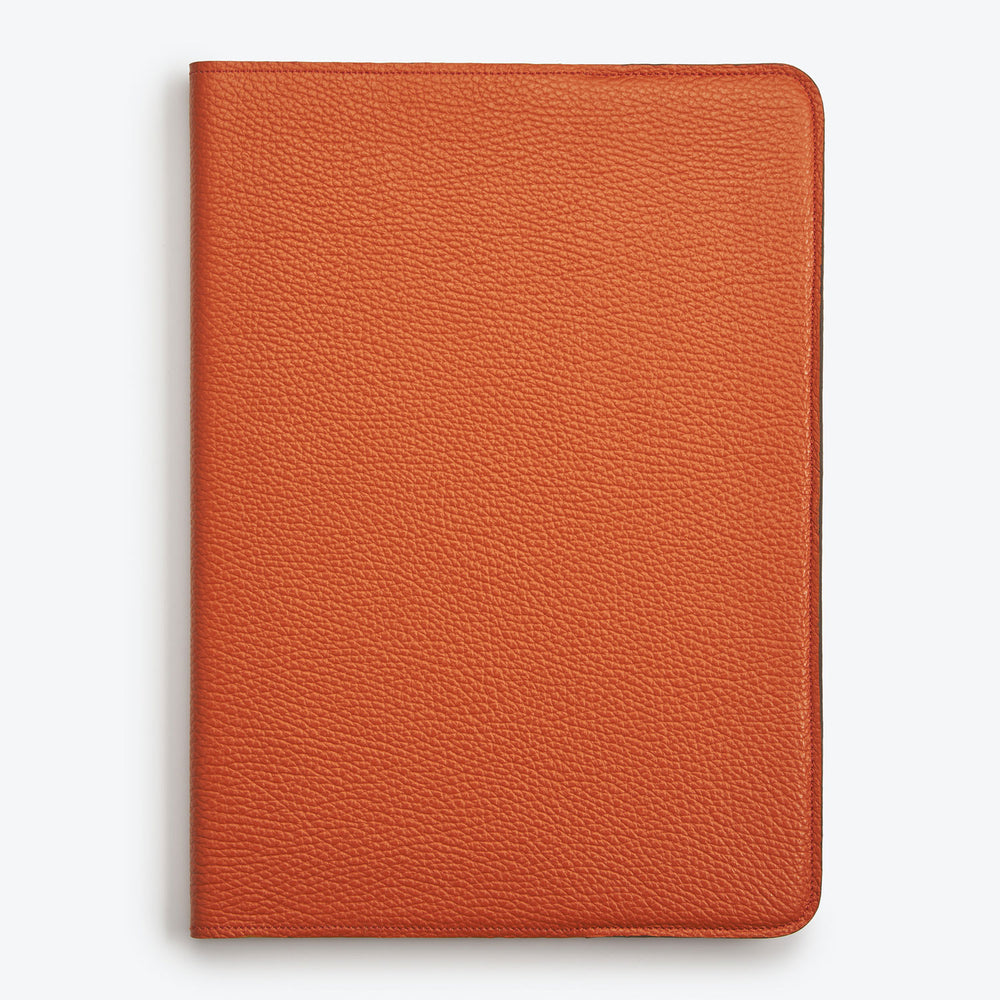 A closed orange Luxury  leather notebook with a visible brand embossing on the back cover.